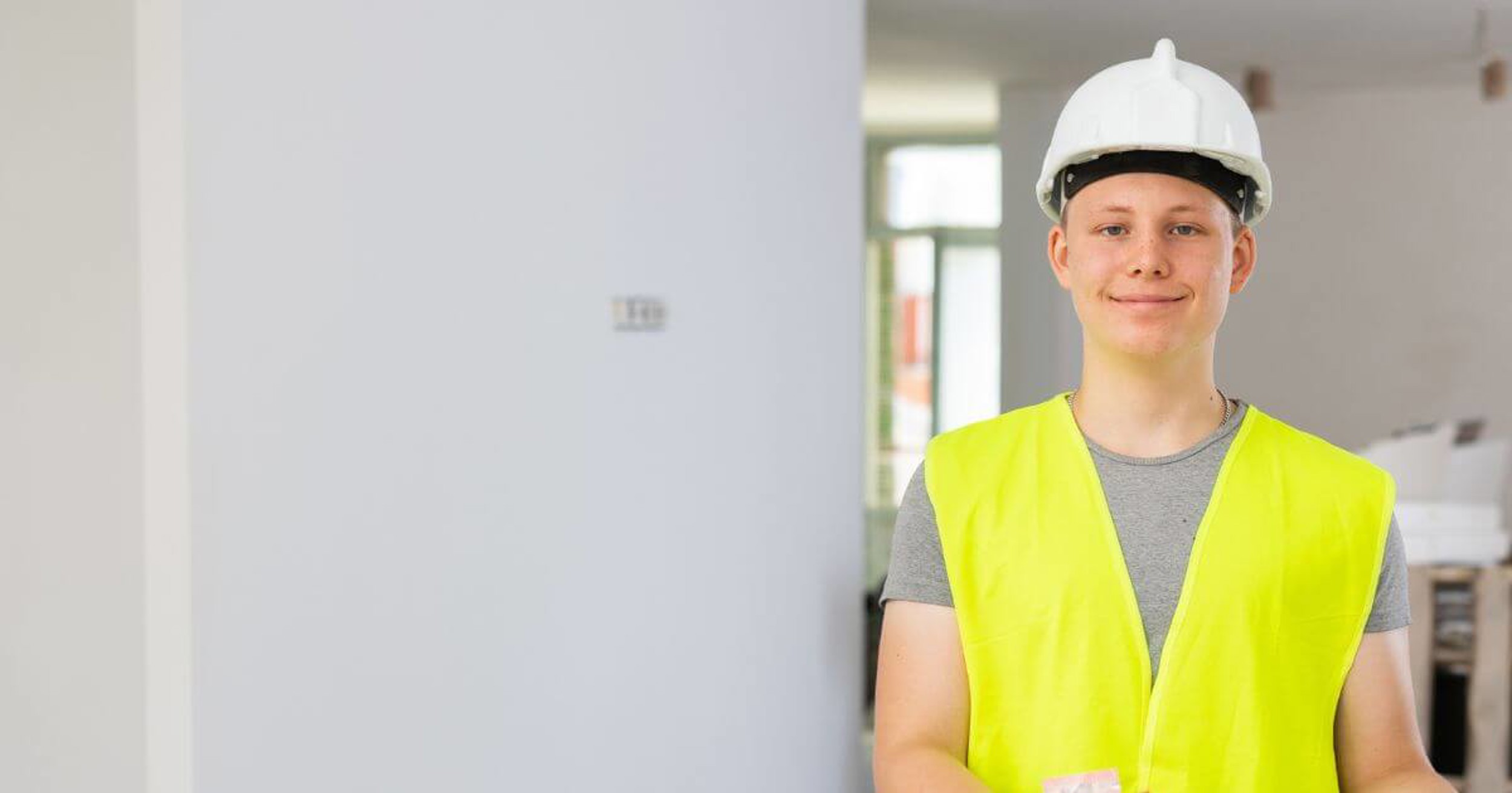 Person smiling at camera wearing high vis jacket and hard hat